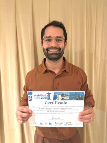 Foto do docente George Valença segurando o prêmio de melhor artigo